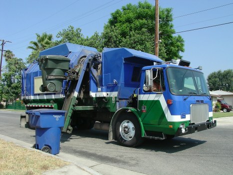 Workers handling commercial bins with PPE in a rubbish collection area